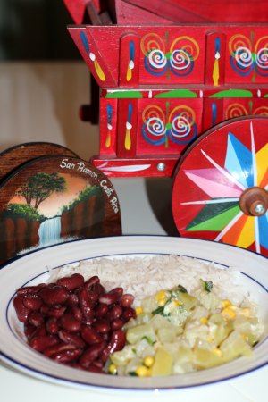 Plate of picadillo de chayote with kidney beans and rice in front of a traditional costa rican ox cart.