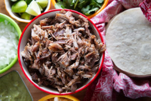 Mexican shredded pork with tortillas, lime, onion and cilantro garnish.
