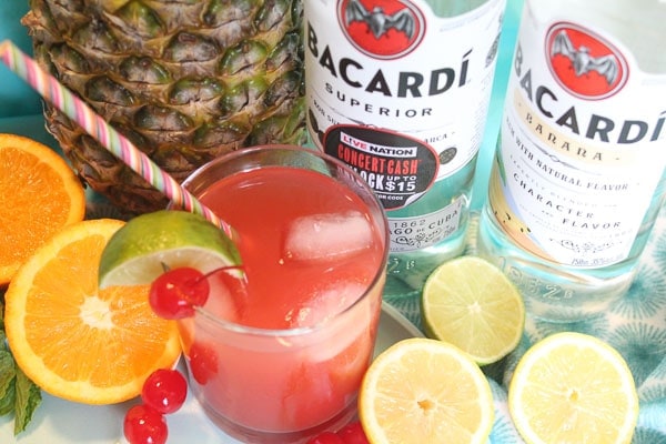 bottles of bacardi with fresh pineapple, lime and glass of rum punch
