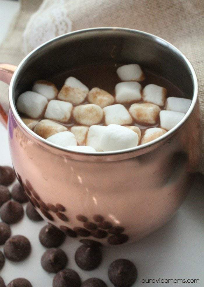 Rose gold mug of hot chocolate topped with mini marshmallows.