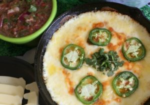 Close-up of fully baked queso fundido garnished with jalapeno slices.