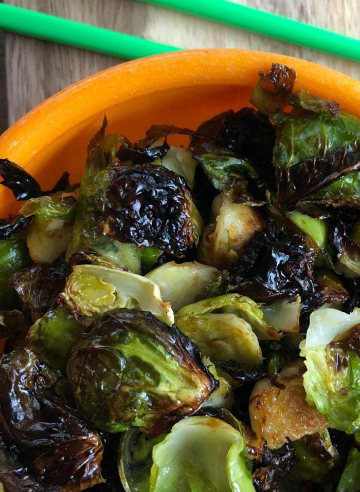 Close-up of crispy Asian Brussels sprouts in an orange bowl.
