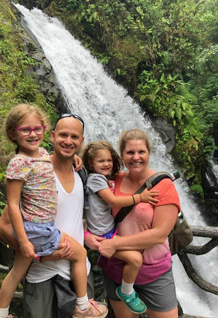 Family standing in front of a waterfall at La Paz Waterfall Gardens.