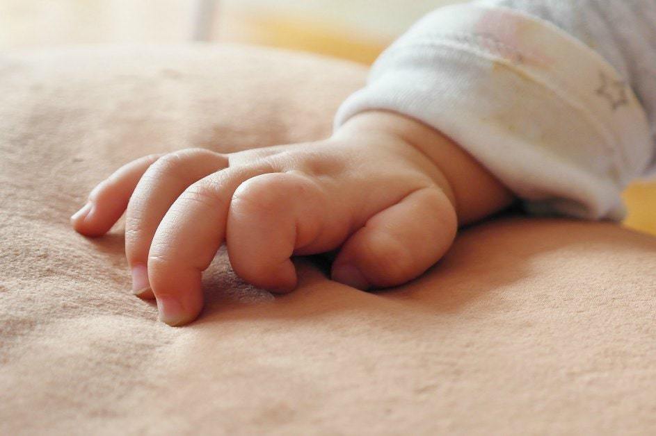 Bilingual baby hand resting on blanket- language acquisition methods