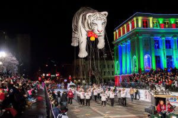 Parade of Lights Denver featuring parade participants holding aloft a giant white tiger balloon.