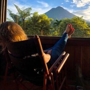 Woman in rocking chair with feet up looking at volcano in Costa Rica.