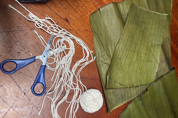 Schere, Schnur und Wegerichblätter, um costaricanische Tamales herzustellen