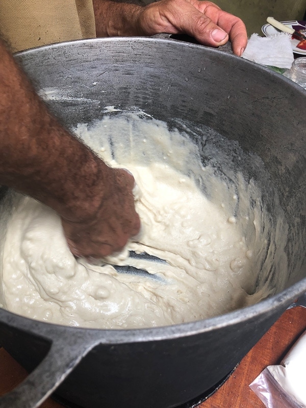 using hands to stir tamale masa in a large stockpot