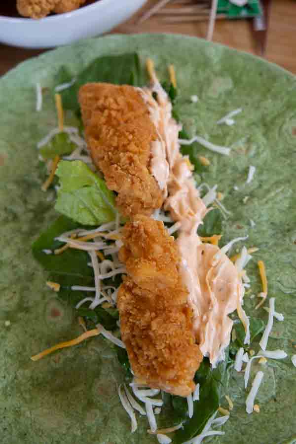 spinach tortilla with lettuce, shredded cheese and crispy chicken tenders