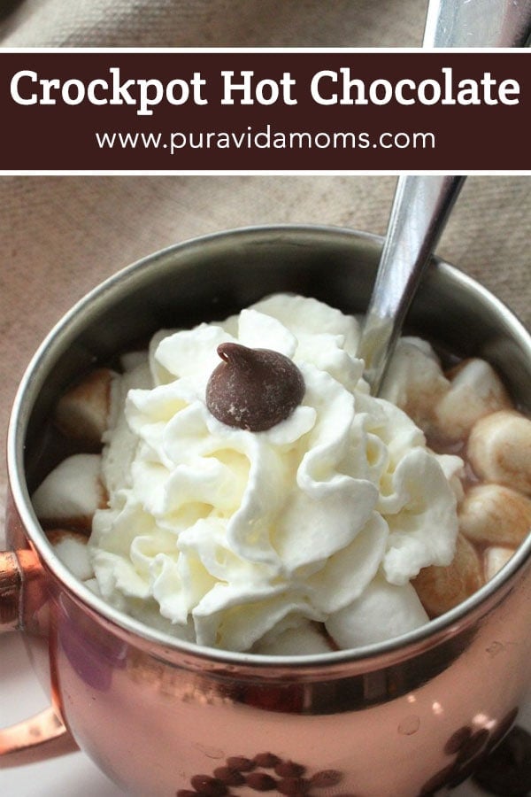A pot of hot chocolate topped with whipped cream.