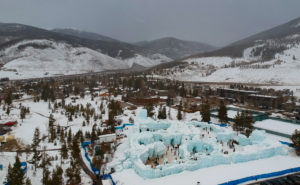 Aerial view of Colorado-based ice palace amidst pine trees and mountains.