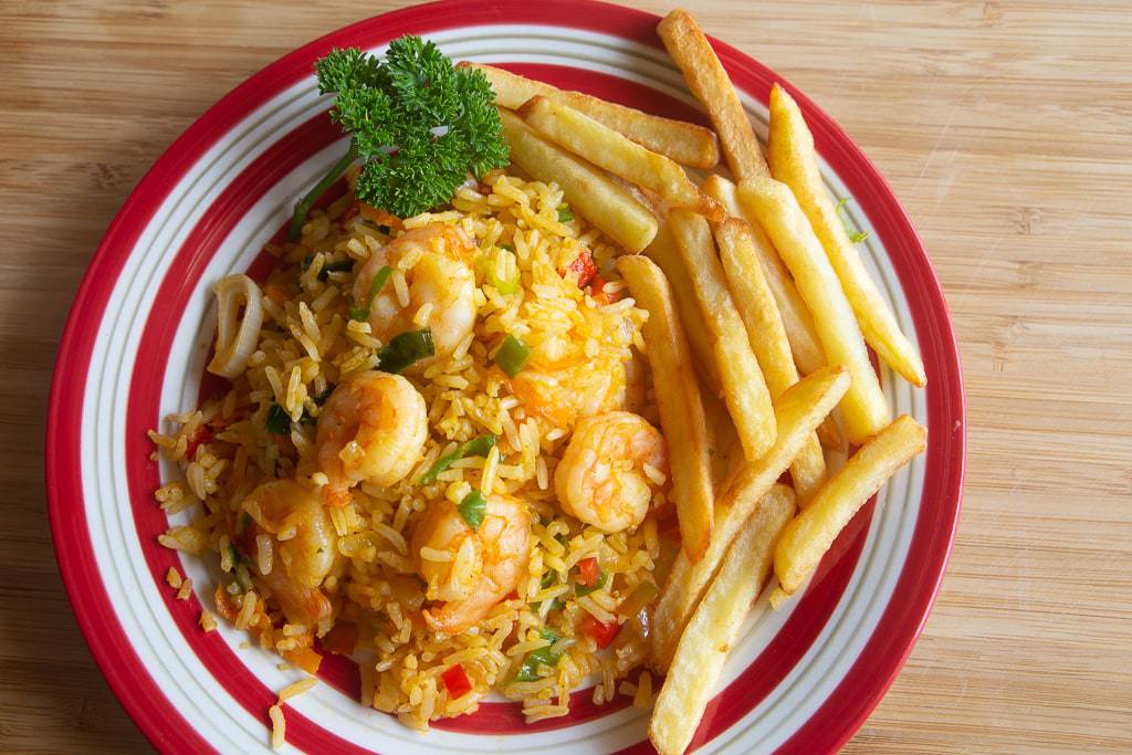 Red and white platter containing shrimp, rice, fries, and a parsley garnish.