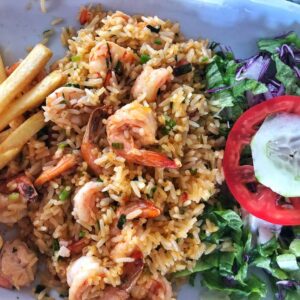 Fried rice with tail on garlic shrimp, tomato, cucumber and lettuce.
