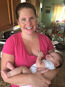 New mother holding her infant daughter in her kitchen.