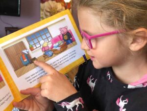 Young girl reading children's book with Spanish text.