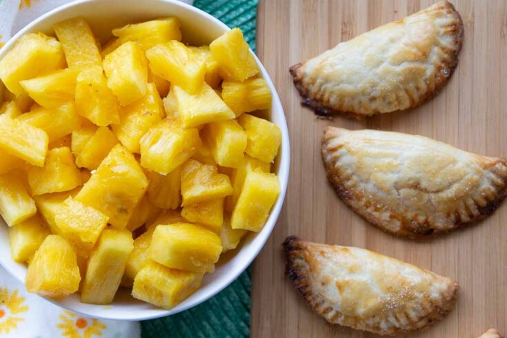 costa rican pineapple empanadas with large bowl of fresh pineapple