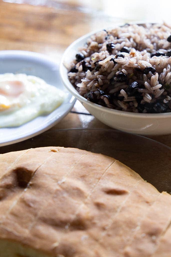 Sliced Costa Rican bread with bean and rice bowl.
