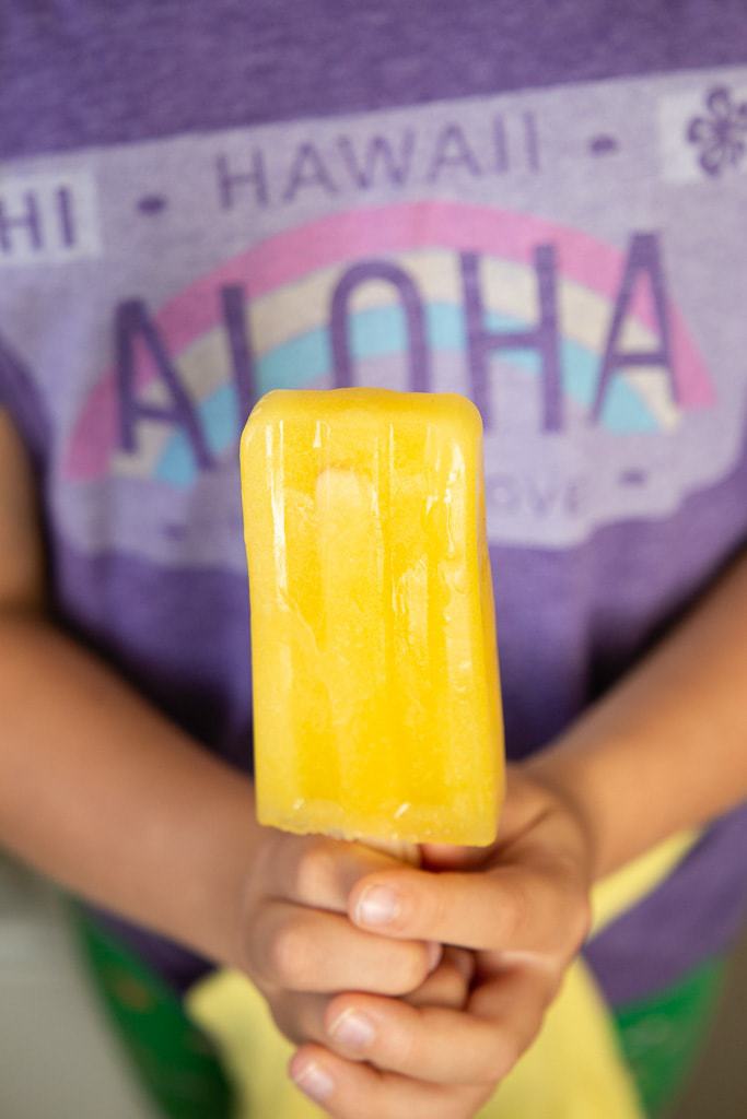 Two hands clasping a mango paleta.