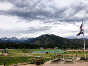 YMCA of the Rockies main field featuring basketball courts, picnic areas, benches, and a statue.