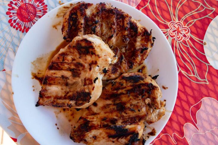 White platter with three grilled chicken breasts heaped on top.