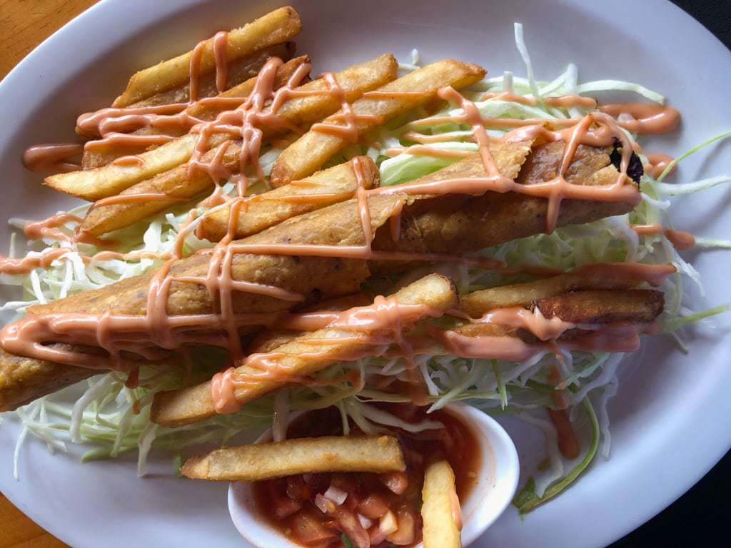 Costa Rican style taco with french fries, shredded cabbage, and fry sauce on a white platter.