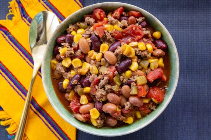 Hearty serving of taco soup with yellow and blue place mats underneath it.