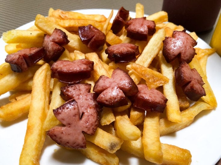 Hot dog sections on a bed of french fries.