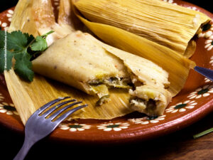 Jalapeño and Chihuahua Cheese Tamales on festive plate with cilantro garnish.