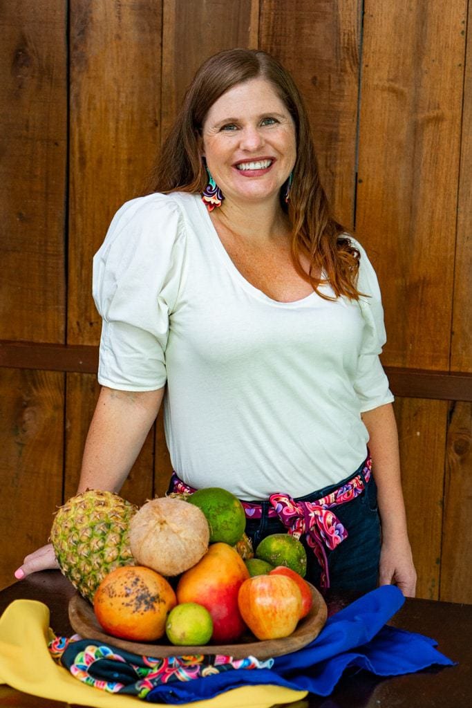 christa jimenez wearing costa rican jewelry and belt standing next to fruit bowl.