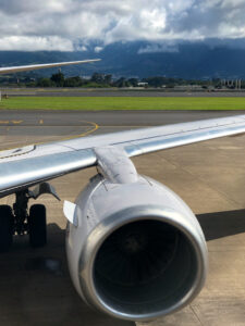 airplane wing on costa rican tarmac with mountains in distance.