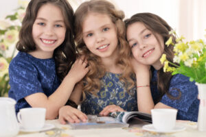 three young girls smiling and reading magazine