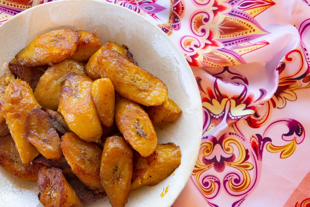fried plantains in a white bowl with a colorful scarf
