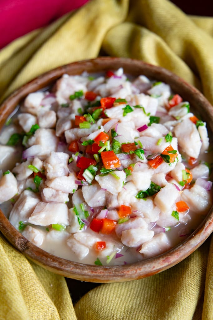 Fish ceviche In a brown serving bowl on a pale yellow cloth.